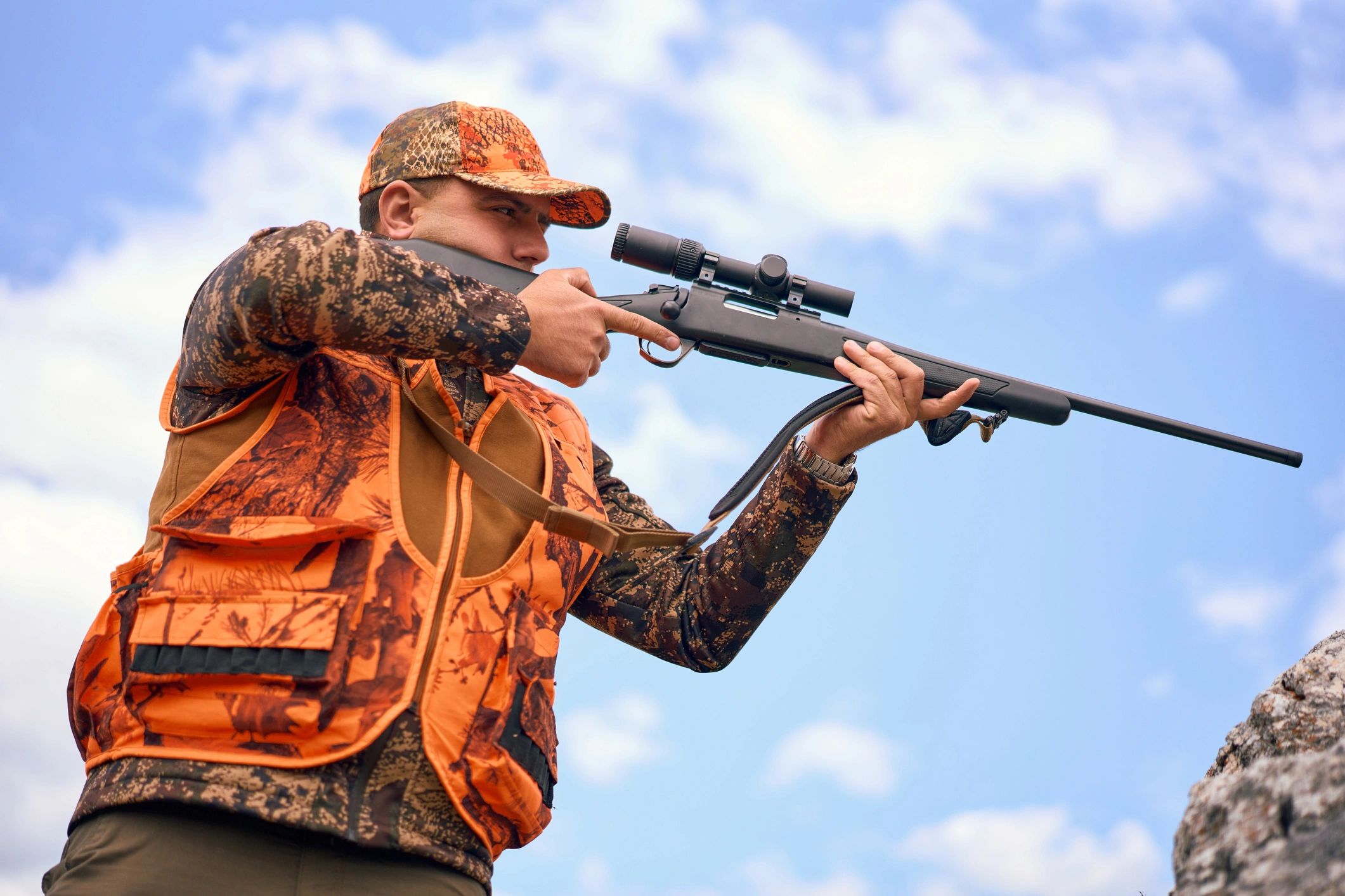 Hunter aiming a scoped air rifle outdoors